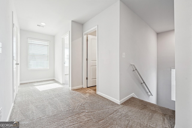 corridor featuring baseboards, carpet flooring, visible vents, and an upstairs landing