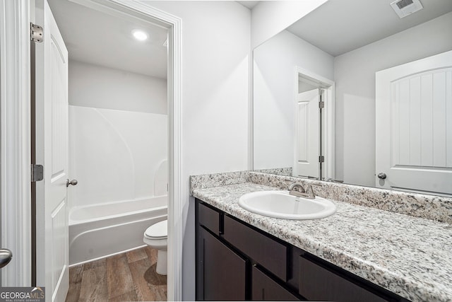 full bathroom with visible vents, toilet, vanity, wood finished floors, and shower / bathtub combination