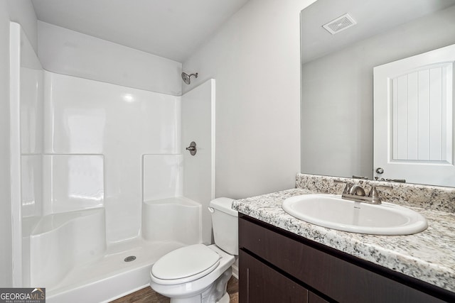 bathroom with toilet, a shower, vanity, and visible vents