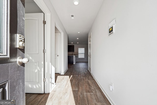 corridor featuring baseboards, wood finished floors, and recessed lighting