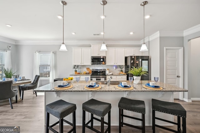 kitchen featuring crown molding, stainless steel appliances, light wood-style flooring, decorative backsplash, and a sink