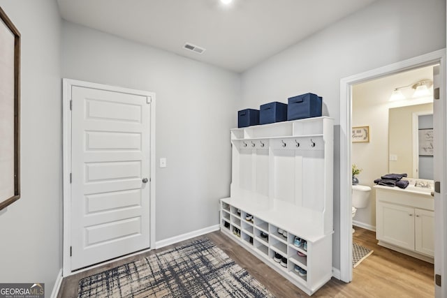 mudroom with a sink, light wood-style flooring, visible vents, and baseboards