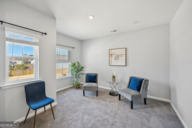 living area with carpet floors, visible vents, and baseboards