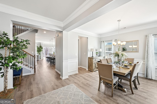 dining space featuring visible vents, light wood-style flooring, stairway, an inviting chandelier, and crown molding