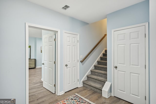 stairs featuring wood finished floors, visible vents, and baseboards