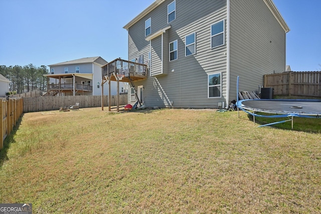 back of property featuring a fenced backyard, stairway, a trampoline, a yard, and central air condition unit