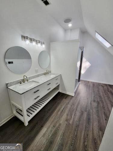 full bath featuring lofted ceiling, wood finished floors, and a sink