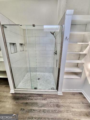 bathroom with a stall shower, baseboards, and wood finished floors