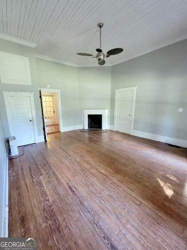 unfurnished living room featuring a fireplace with flush hearth, crown molding, ceiling fan, and wood finished floors