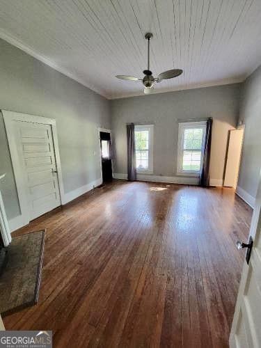 unfurnished living room with a ceiling fan, baseboards, and wood finished floors