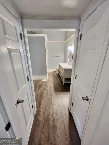 corridor with dark wood-style floors and ornamental molding