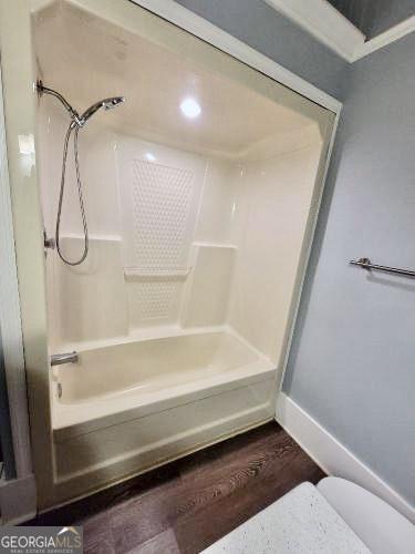 bathroom with  shower combination, baseboards, and wood finished floors