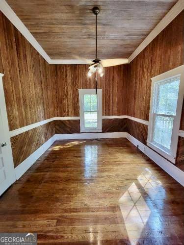 unfurnished dining area featuring wooden walls, baseboards, and wood finished floors