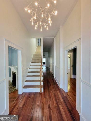 stairway featuring a fireplace, a towering ceiling, an inviting chandelier, and wood finished floors