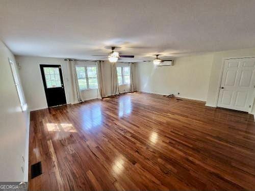 unfurnished living room with ceiling fan, wood finished floors, and visible vents