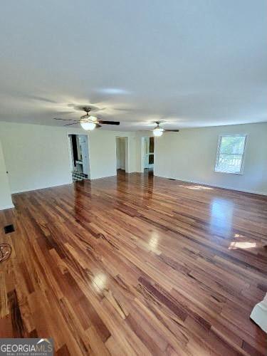 unfurnished living room featuring a ceiling fan and wood finished floors