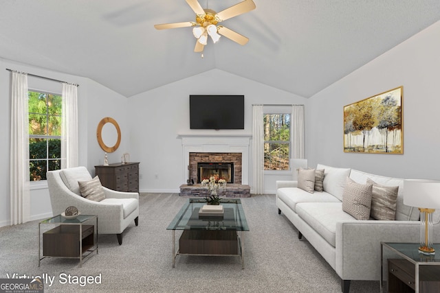 living area with vaulted ceiling, carpet flooring, a healthy amount of sunlight, and ceiling fan