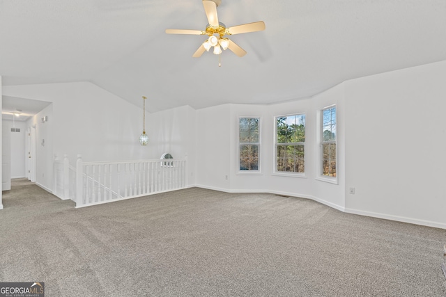 carpeted spare room featuring vaulted ceiling, baseboards, and ceiling fan