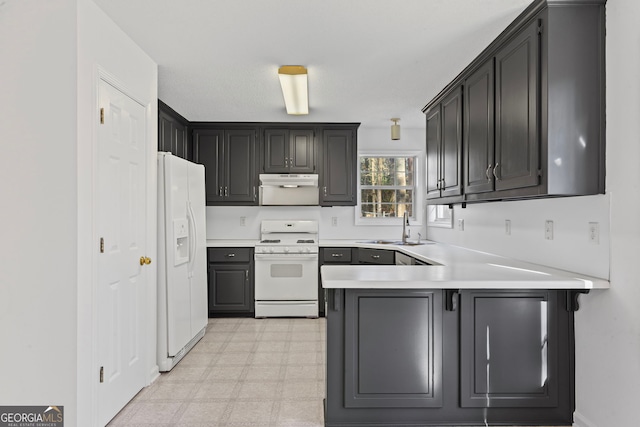 kitchen featuring under cabinet range hood, light floors, a peninsula, white appliances, and a sink