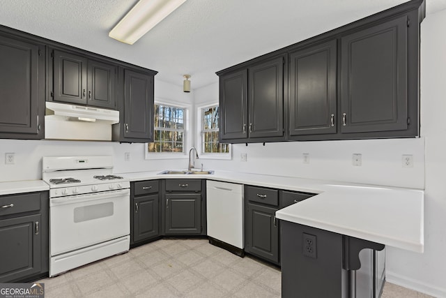 kitchen featuring under cabinet range hood, a sink, white appliances, light countertops, and light floors