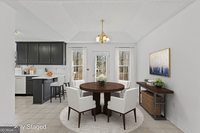 dining space with an inviting chandelier, light floors, a raised ceiling, and a textured ceiling