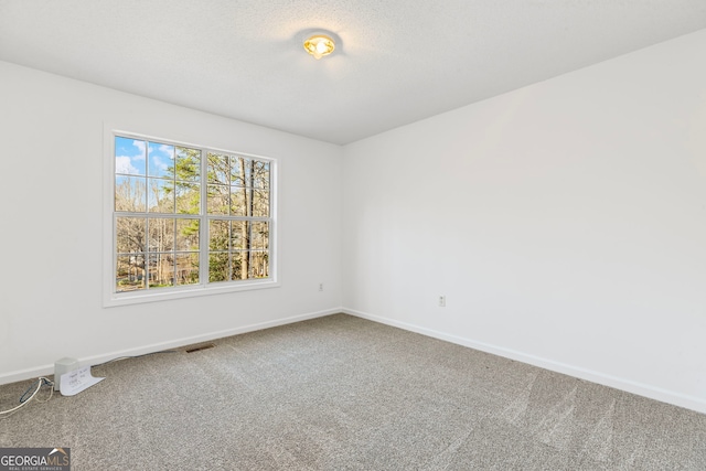 carpeted spare room with visible vents, a textured ceiling, and baseboards