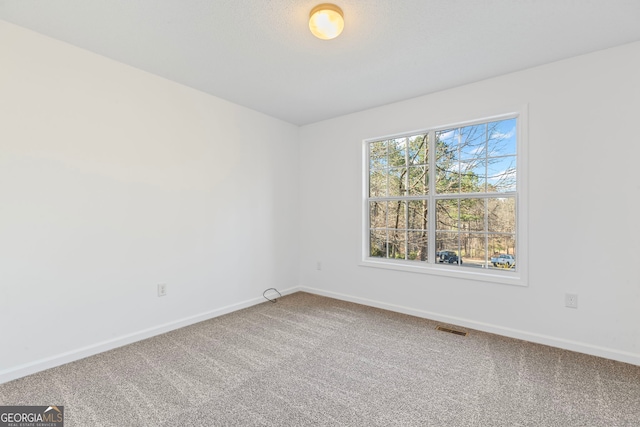 carpeted empty room featuring visible vents and baseboards