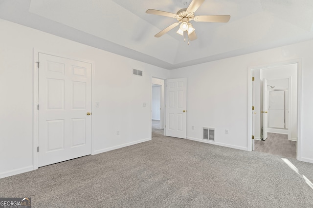 unfurnished bedroom with visible vents, a raised ceiling, baseboards, and carpet floors