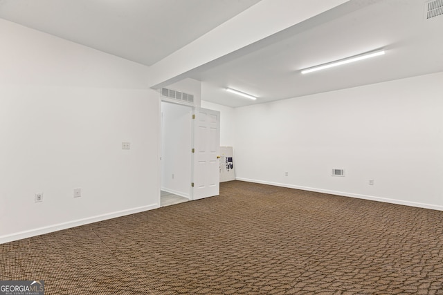 unfurnished room featuring visible vents, baseboards, and dark carpet