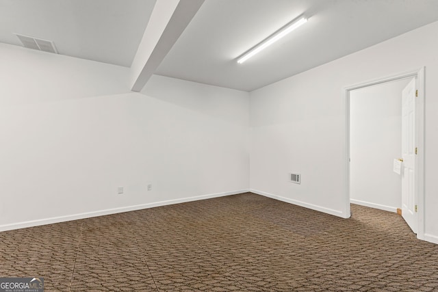 spare room with visible vents, dark carpet, and baseboards