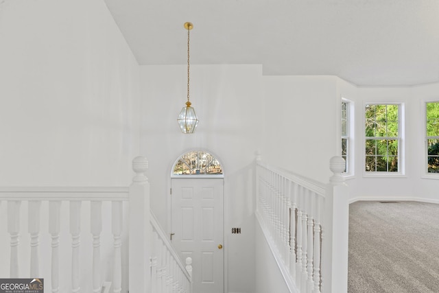 carpeted entryway featuring an inviting chandelier and visible vents