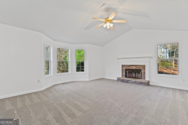 unfurnished living room with a ceiling fan, baseboards, a fireplace, vaulted ceiling, and carpet flooring