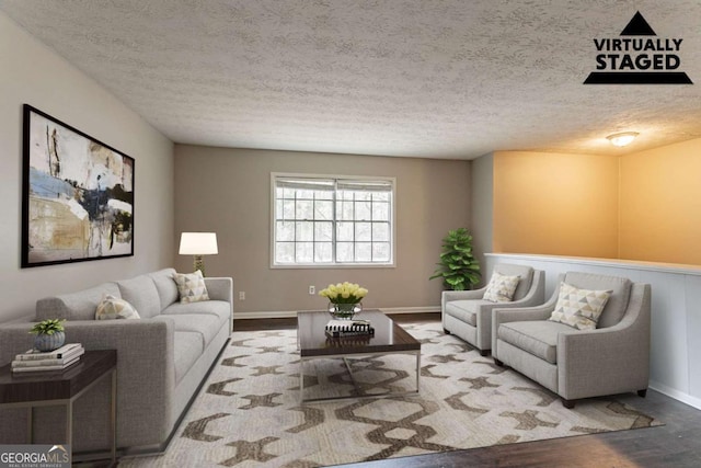 living room with a textured ceiling, baseboards, and wood finished floors