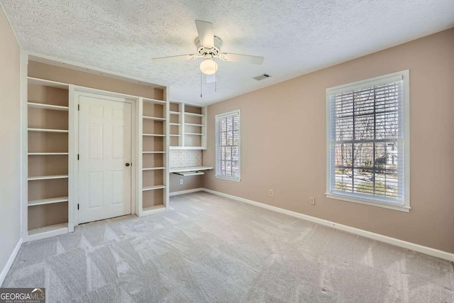 unfurnished bedroom with a textured ceiling, carpet floors, a ceiling fan, visible vents, and baseboards