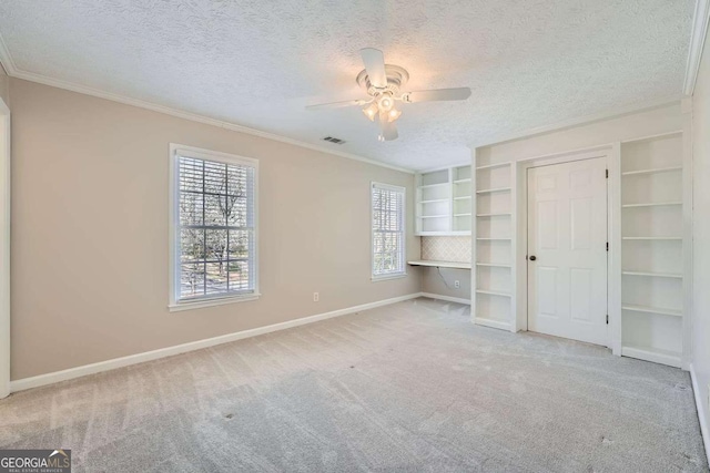 unfurnished bedroom featuring a textured ceiling, carpet floors, visible vents, baseboards, and crown molding