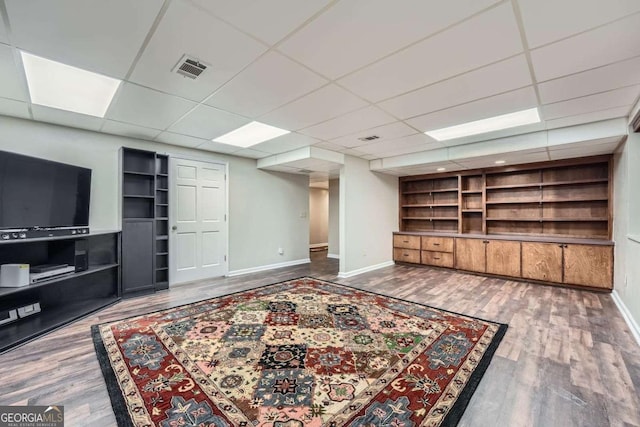 interior space featuring a paneled ceiling, visible vents, baseboards, and wood finished floors