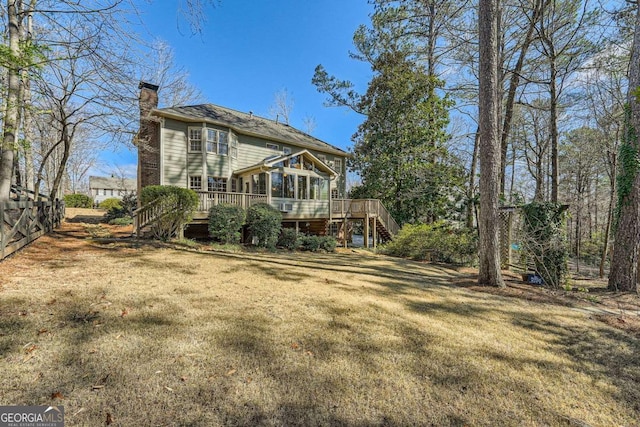 back of property with a deck, fence, stairs, a lawn, and a chimney