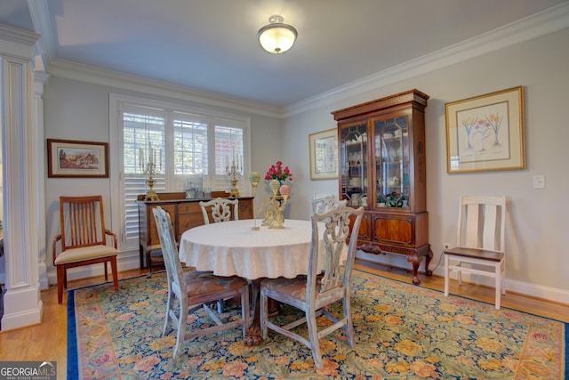 dining space with light wood-style floors, ornate columns, ornamental molding, and baseboards