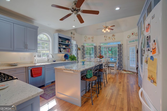 kitchen with dishwashing machine, a kitchen island, freestanding refrigerator, a kitchen bar, and open shelves