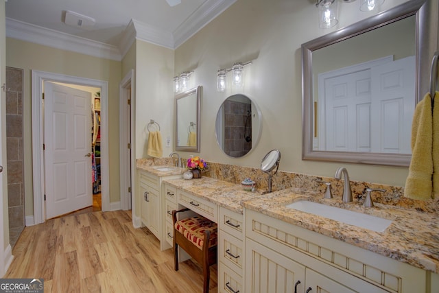 bathroom with double vanity, ornamental molding, a sink, and wood finished floors