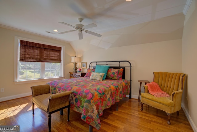 bedroom featuring wood finished floors, visible vents, baseboards, vaulted ceiling, and ornamental molding