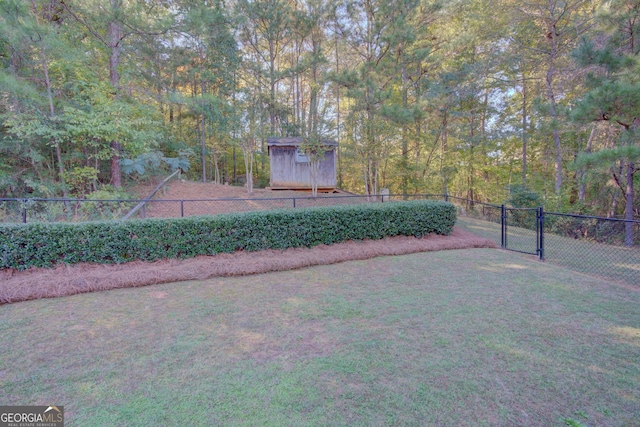 view of yard featuring a shed, an outdoor structure, fence, and a gate