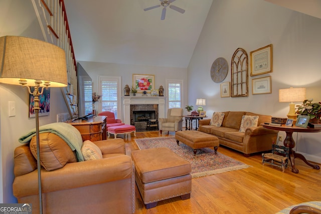 living room with visible vents, ceiling fan, light wood-style floors, a fireplace, and high vaulted ceiling