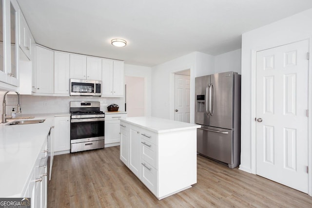 kitchen featuring a kitchen island, light wood-style flooring, a sink, stainless steel appliances, and tasteful backsplash