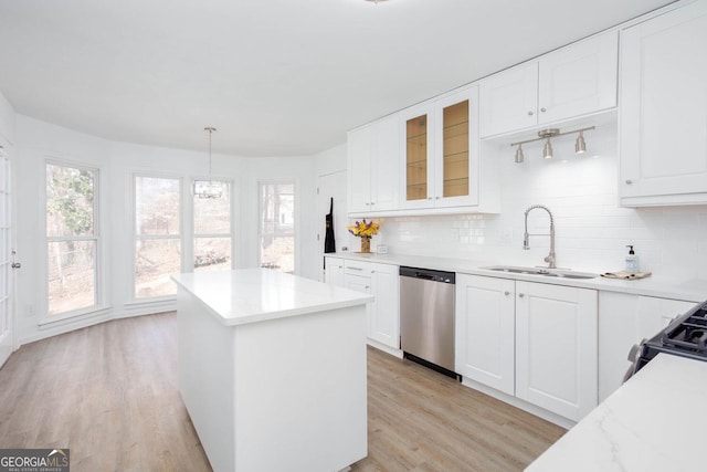 kitchen featuring a kitchen island, decorative backsplash, light wood-style flooring, stainless steel dishwasher, and a sink