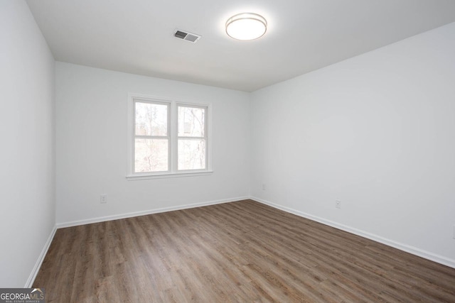 unfurnished room with visible vents, baseboards, and wood finished floors