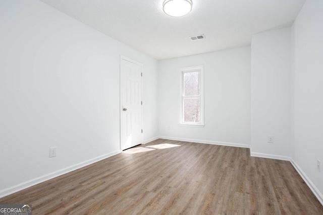 unfurnished room with visible vents, baseboards, and wood finished floors