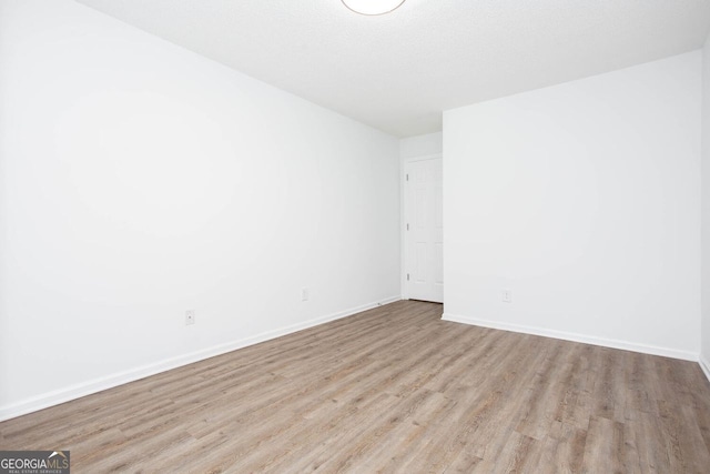 spare room with a textured ceiling, baseboards, and wood finished floors