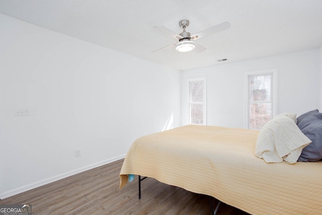 bedroom featuring visible vents, ceiling fan, baseboards, and wood finished floors