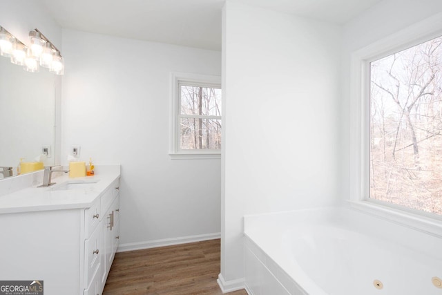 bathroom featuring vanity, a jetted tub, wood finished floors, and baseboards